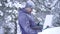 Frozen man in cold winter enjoys a laptop
