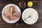 Frozen pieces of pollock fillet in plate, bowl with flour, spoon, salt, condiment in bowl on wooden table. Top view