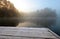 Frozen pier on lake in cold still foggy morning