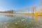 Frozen pond with bare trees on the shore and remnants of snow