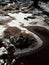 Frozen pool and hoarfrost grass on the mountain. Frozen grass and boulders bellow trees