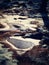 Frozen pool and hoarfrost grass on the mountain. Frozen grass and boulders bellow trees