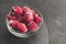 Frozen raspberries in plate on black table. Winter vitamin dessert