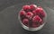 Frozen raspberries in plate on black table. Winter vitamin dessert