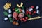 Frozen raspberry, blackberry, strawberries mint leaves, pieces of ice on a black shale board, slices of lemon, nuts, wheat, top vi