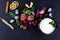Frozen raspberry, blackberry, strawberries, yoghurt plate mint leaves, pieces of ice on a black shale board, slices of lemon, nuts