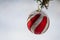 Frozen Red Striped Christmas Ornament Decorating a Snowy Outdoor Tree