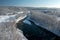 A frozen river flows between trees covered with white snow. On a frosty sunny December day in a forest covered with