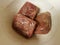 Frozen seasoned beef meat squares in white plastic container