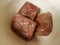 Frozen seasoned beef meat squares in white plastic container