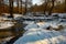 Frozen sluice and stream in snowy landscape with trees