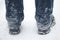 Frozen snow on jeans and black boots of a man in winter, rear view.