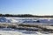 Frozen water and snow piles  blue sky tire marks in front