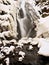 Frozen waterfall. Winter creek, icy stones and branches