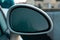 Frozen white rearview mirror of a parked car in a outdoor parking, early winter frost