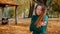 Frozen young attractive brunette woman is walking in the park on a background of yellowed trees in autumn