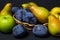 Fruit on a black background. Plums, pears and apples lie side by side.