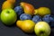 Fruit on a black background. Plums, pears and apples lie side by side.