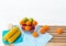The fruit bowl with red apple,green apple and orange put beside dish of yellow corn,four oranges put on wooden timber board