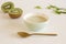 Fruit breakfast of fresh homemade green smoothie kiwi in a porcelain bowl. Golden small spoon in the foreground. Healthy