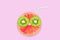 Fruit creative face with slices of grapefruit and kiwi, drinking straw on pink background, juice and summer concept