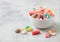 Fruit flavour gums candies with a sour sugar coating in ceramic bowl on light background