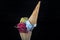 Fruit ice cream scoops overhead on a cornet, served with several colorful spoons isolated on black background