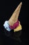 Fruit ice cream scoops overhead on a cornet, served with several colorful spoons isolated on black background