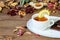 Fruit lemon tea cup and chocolate on the white saucer. Dry autumnal leaves and petals on the wooden table. New autumn season, home