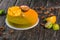 Fruit mousse cake with a mango and litchi decor on a wooden stand