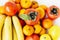 Fruit plate on white background. Mandarins, bananas, persimmons and lemons