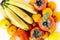 Fruit plate on white background. Mandarins, bananas, persimmons and lemons