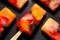 Fruit popsicles, homemade fruit ice lolly of various fruits with the addition of citrus lemonade on a black background, top view.