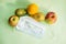 Fruit and protective mask on a mint background, fruit harvest, protection from coronavirus, fruit from China. Close-up