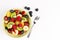 Fruit Salad in Green Bowl, blueberries and fork on white Table, Top View. copy space