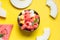 Fruit salad of watermelon, melon and peach in coconut bowl in hands of child on yellow background