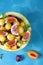 Fruit salad with yellow watermelon, fig, nectarine, plum, bilberry, apple, banana and honey