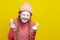 Fruit Series. Winsome Girl In Coral Knitted Clothing Holding Two Acid Yellow Lemon Slices In Front of Face Over Yellow Background