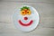 fruit smile on a white plate of fresh red strawberries and apricots and watermelon on the table