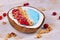 Fruit smoothie bowl in coconut shell naturally dyed with blue spirulina powder and topped with cranberries and hazelnuts