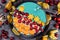 Fruit smoothie bowl with healthy natural green spirulina powder decorated with cranberries, physalis and kaki fruits and puffed qu