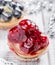 Fruit tarts with berries and strawberry on light background close up.