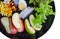 Fruit and vegetable salad in black plate on white background