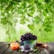 Fruit on wooden table in green sunlight garden. Eco green grapes tree background