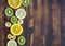 Fruits and berries kiwi, lemon, banana, raspberry, currant, orange on wooden background.