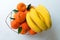 Fruits. A bunch of bananas and tangerines in a vase on a white background. Flat lay.