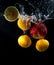 Fruits clementine, lemon slice and apple splash of water on black