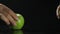 Fruits of green apple on the black table. Black background. Hand picks up the apples. Close-up shooting