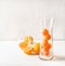 Fruits ice cubes of orange  juice in jug and glasses for refreshing drinks on white table . Summer drink preparation