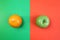 Fruits orange and green apple lie on the halves of multi-colored paper